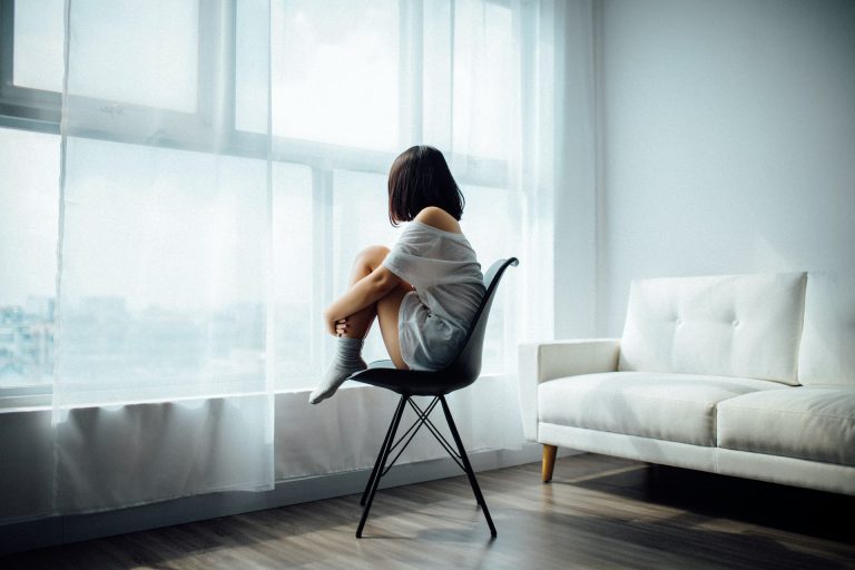Woman sitting in front of a window, battling with post-vacation depression